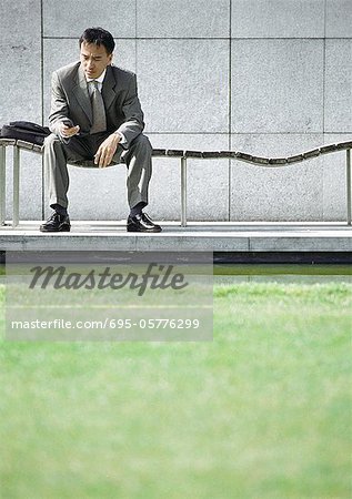 Businessman on bench looking at cell phone