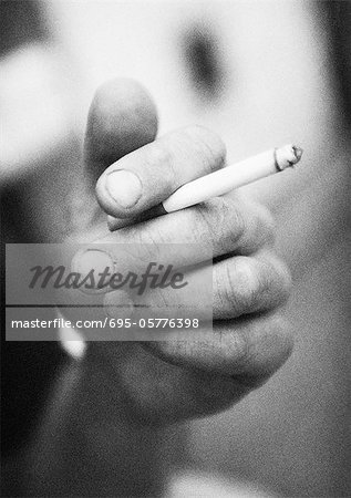 Hand holding cigarette, close-up, b&w