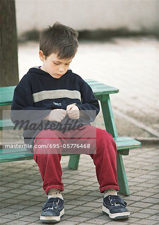 Kind sitzt auf Bank