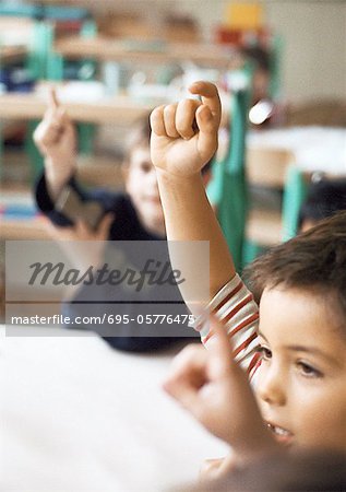 Children raising hands, close-up, blurred