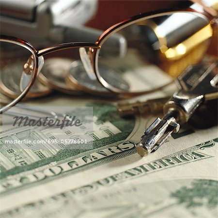 Glasses, keys, cell phone lying on U.S. money