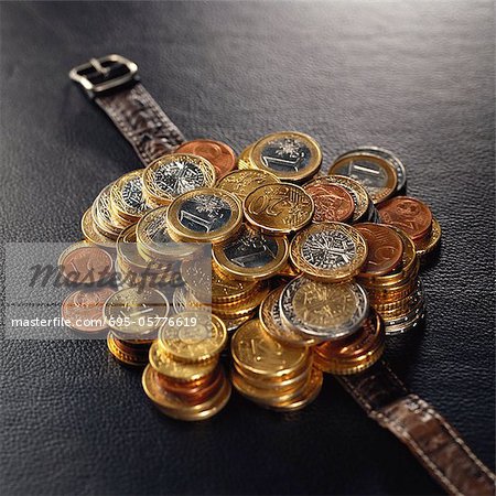 Pile of assorted euro coins on top of watch band