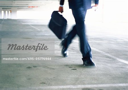 Businessman walking, lower section, blurred