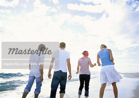 Group of friends walking on beach, rear view