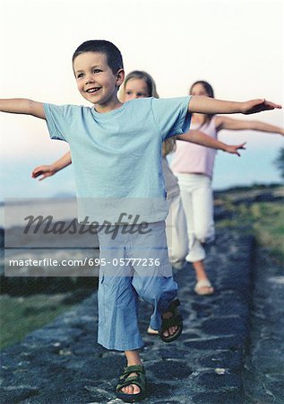 Children walking single file with arms out