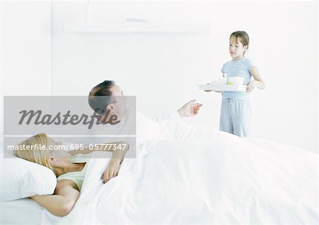 Girl bringing parents breakfast in bed