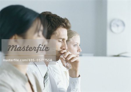 Colleagues staggered, man in center holding glasses, eyes closed