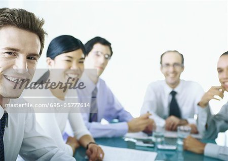 Businesspeople sitting around table, smiling