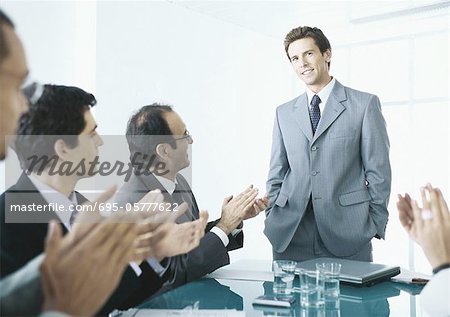 Gens d'affaires assis applaudissant l'homme debout à la fin du tableau