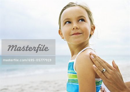 Petite fille ayant frotté sur les épaules de protection solaire