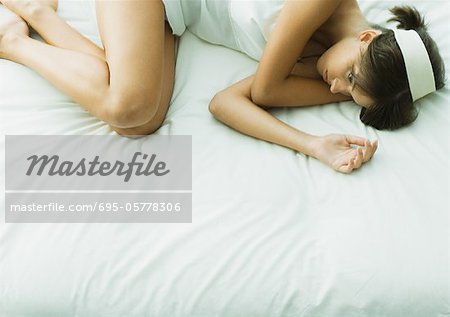 Young woman lying on bed with eyes open