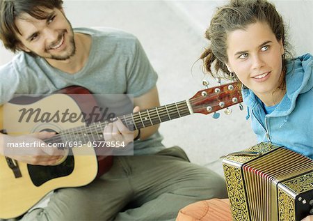 Jeune homme jouer de la guitare, jeune femme jouant accordéon