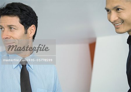Two businessmen, smiling and looking out of frame