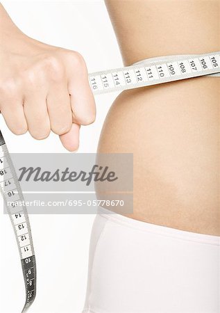 Woman squeezing measuring tape around waist