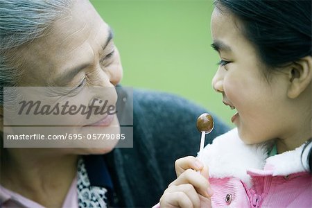 Girl eating lollipop, looking at grandmother, close-up