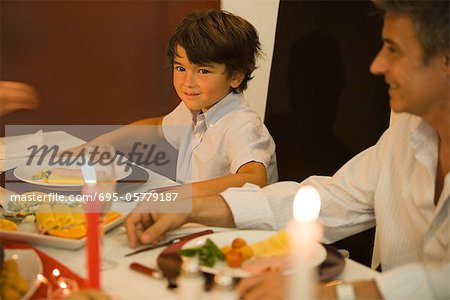 Homme et garçon assis à table, sourire