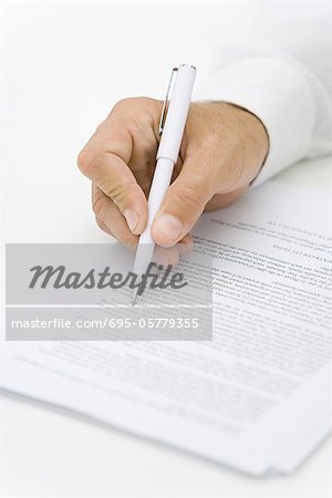 Businessman reviewing contract with pen, cropped view of hand