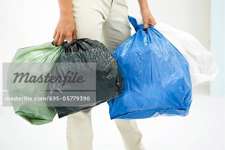 Female carrying several bags of garbage, cropped view