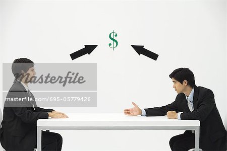 Two businessmen face to face, one reaching to offer his hand, dollar sign and arrows between them