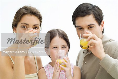 Famille boire le jus d'orange, tous regardant de caméra