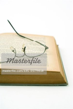 Pair of glasses resting on yellowed page of open book