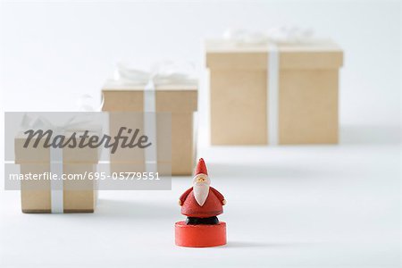 Santa Claus figurine standing in front of Christmas gifts