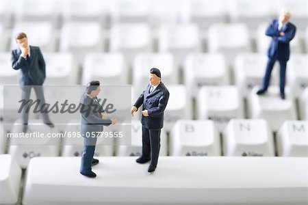 Les hommes d'affaires de miniature debout face à face sur le clavier de l'ordinateur