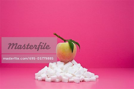 Food concept, fresh peach on top of pile of sugarcubes