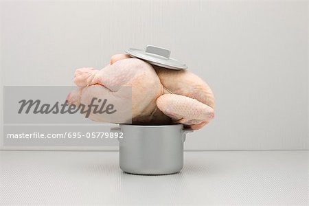 Food concept, raw whole chicken atop too small pot