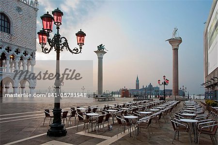 Cafe tables and chairs in the early morning in St. Marks Square, with Isola di San Giorgio Maggiore in distance, Venice, UNESCO World Heritage Site, Veneto, Italy, Europe