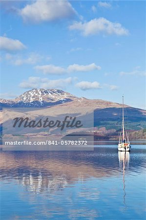 Picturesque tranquil Loch Lomond with sailing boat, snow covered Beinn Uird behind, from Luss Jetty, Luss, Argyll and Bute, Scotland, United Kingdom, Europe