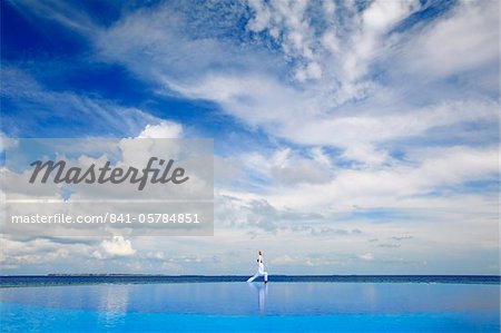 Young man meditating by infinity pool, Maldives, Indian Ocean, Asia