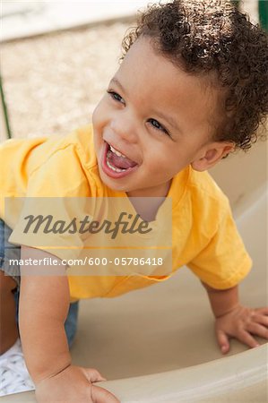 Portrait of Young Boy Climbing up Slide in Playground