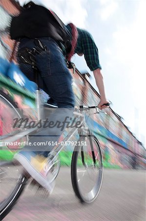 Mid adult cyclist riding bike across bridge