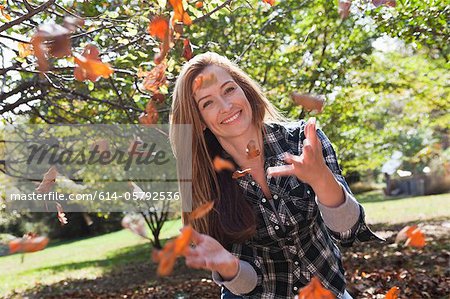 Femme jetant l'automne laisse dans l'air