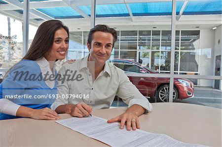 Couple de signer des documents pour voiture neuve