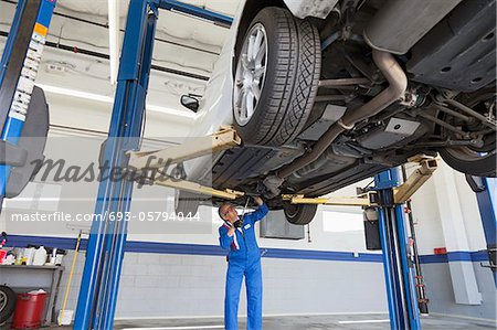 Low angle view of mechanic working under car