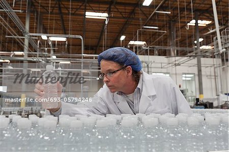 Travailleur de contrôle de la qualité contrôle de bouteilles d'eau à l'usine d'embouteillage