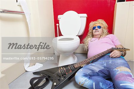 Homme couché dans les toilettes avec une guitare