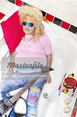 Guitarist lying in bathtub