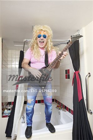 Full-length of guitarist playing guitar in bathroom