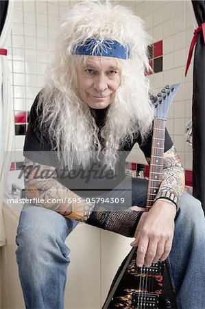 Portrait of guitarist sitting in bathroom