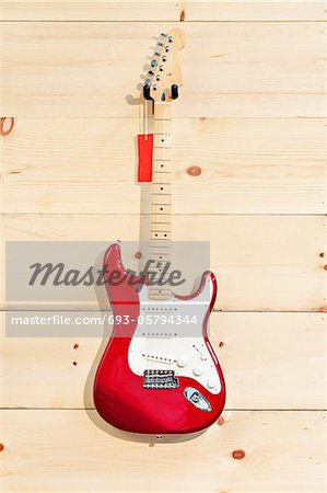 Fender Stratocaster red and white guitar on wood grain wall