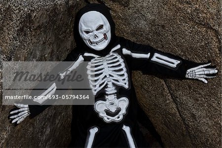 Junge verkleidet als Skelett posiert auf einem Felsen