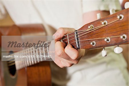 Close-up view of man's hand playing guitar