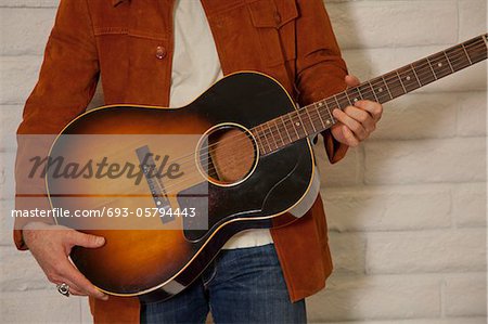Close-up of mid adult man's torso holding guitar