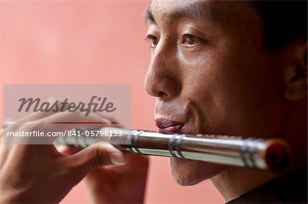 Closeup view of a young Chinese man playing a traditional Chinese flute, Beijing, China, Asia