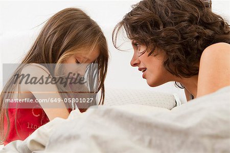 Mutter und Tochter auf dem Bett im Gespräch Mutter und Tochter auf dem Bett im Gespräch