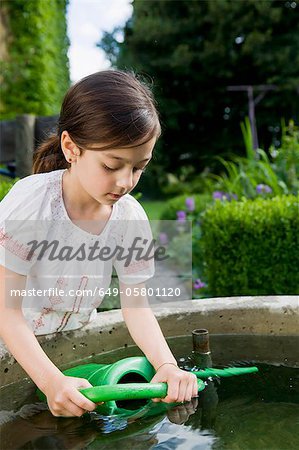 Girl filling up watering can in fountain