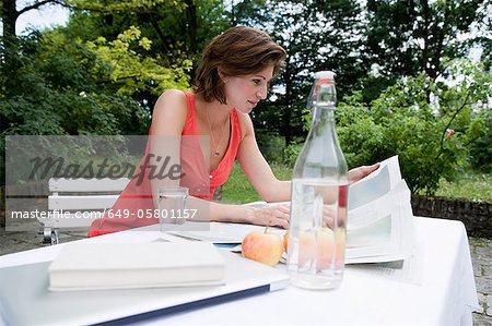 Woman reading newspaper in backyard